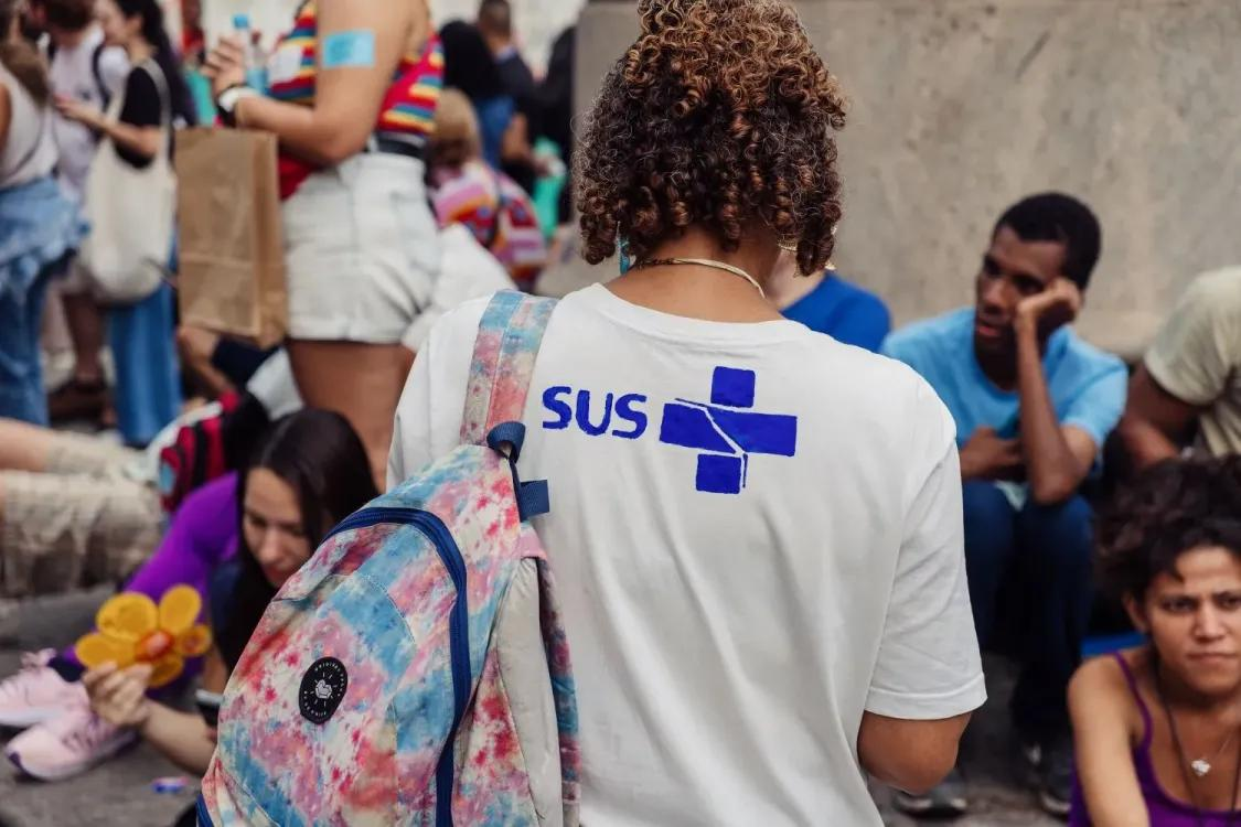 A woman wearing a white T-shirt with the logo SUS on the back