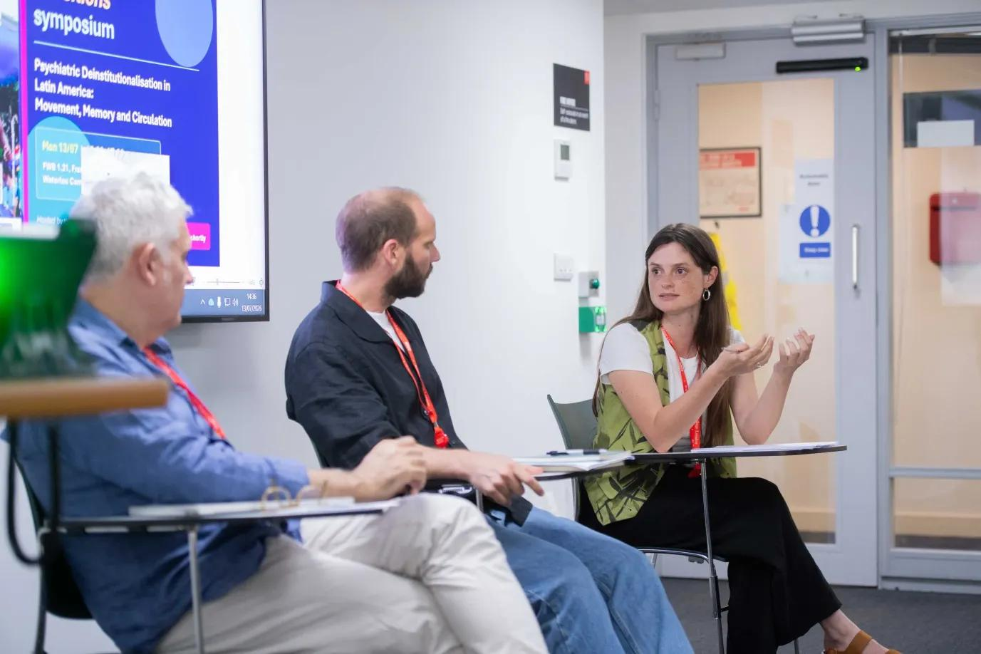 Sofía Bowen speaking during the first symposium panel, alongside Felipe Szabzon and Francisco Ortega