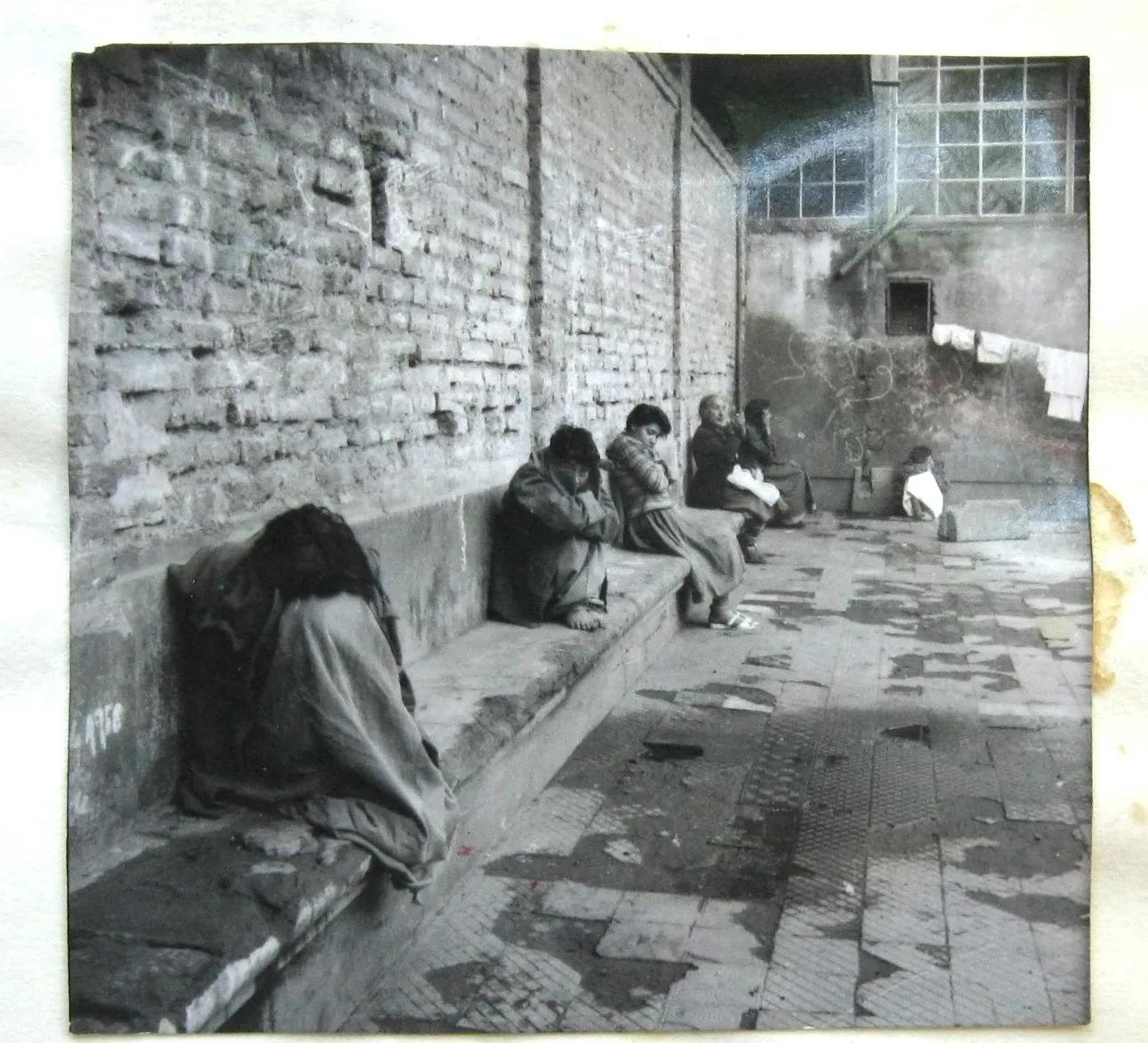 A handful of people huddled on stone seating in a courtyard